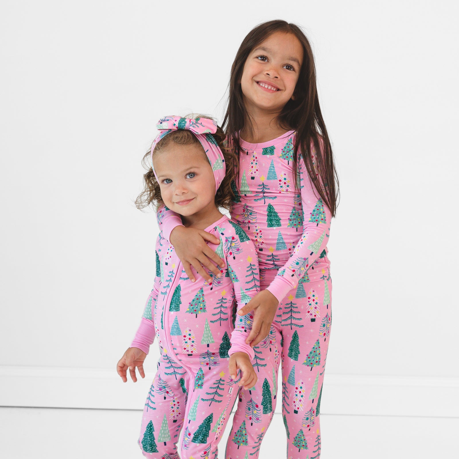 Image of two children hugging and wearing matching Pink Twinkling Trees pajamas