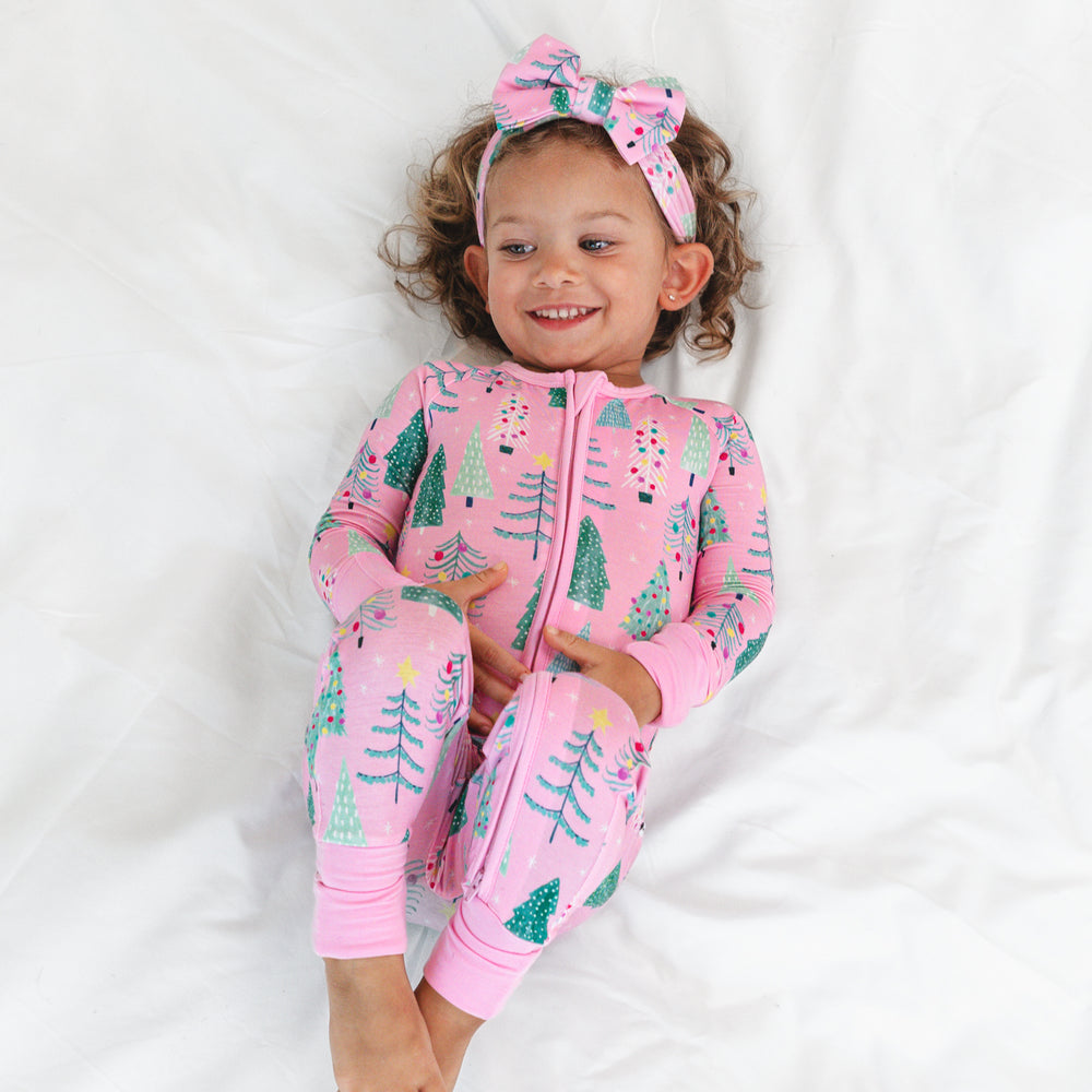 Image of a child laying on a blanket wearing a Pink Twinkling Trees Luxe Bow Headband and matching Zippy