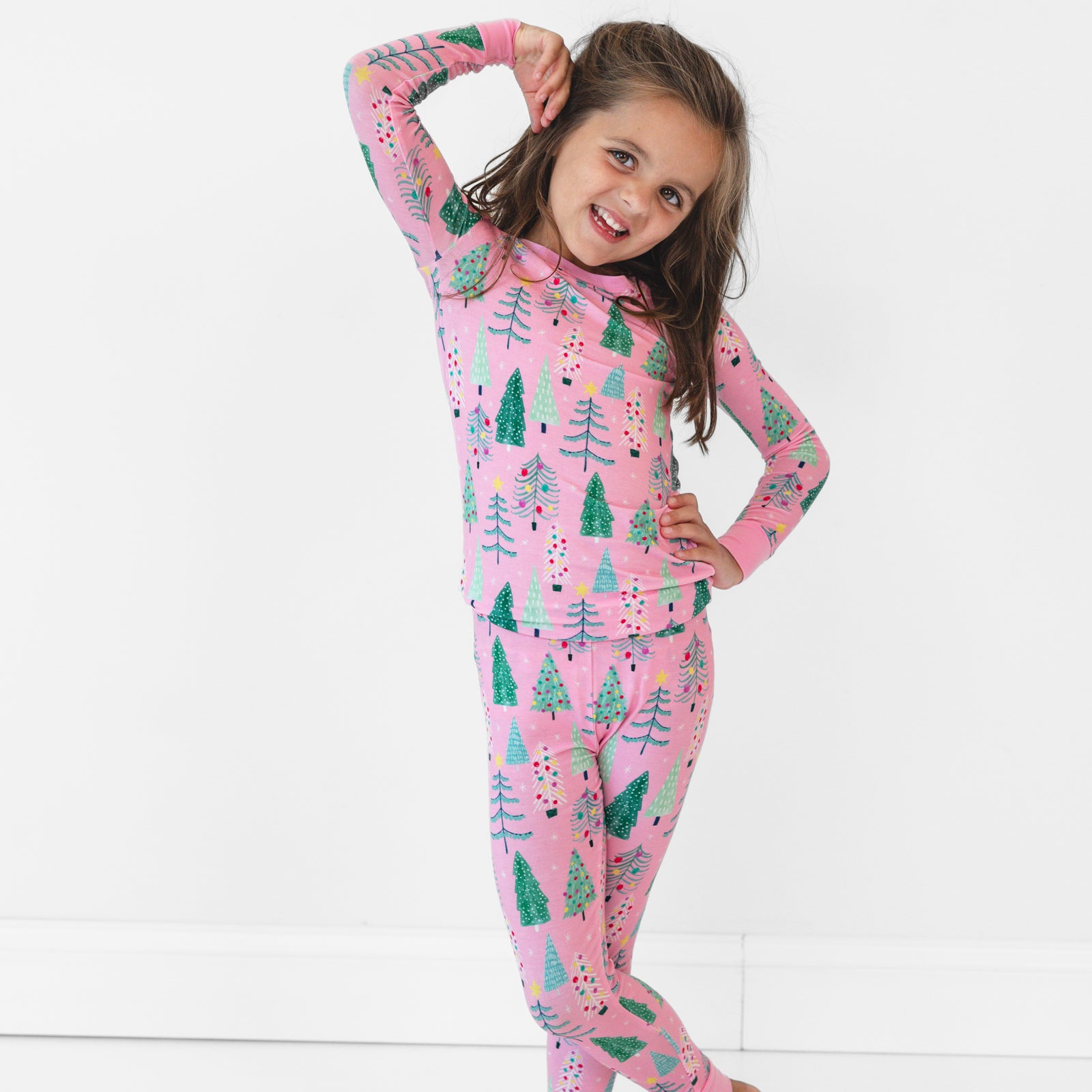 Image of a child posing and wearing a Pink Twinkling Trees Two-Piece Pajama Set