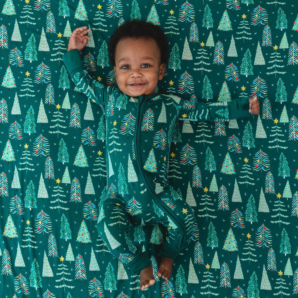 Top view of baby laying down on the Green Twinkling Trees Large Cloud Blanket® while wearing the Green Twinkling Trees Zippy