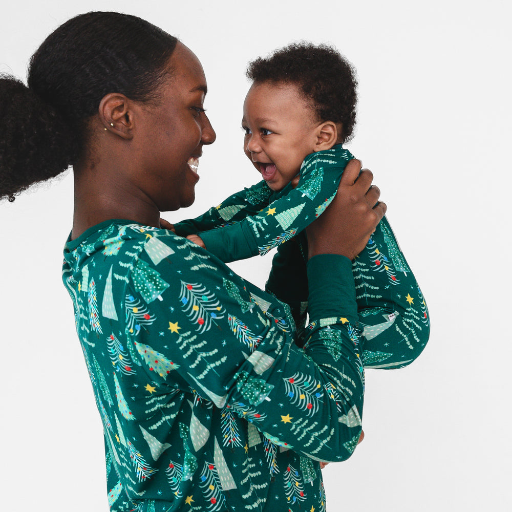 Female model holding baby while wearing the Green Twinkling Trees Women's Pajama Top . Baby is wearing the Green Twinkling Trees Zippy