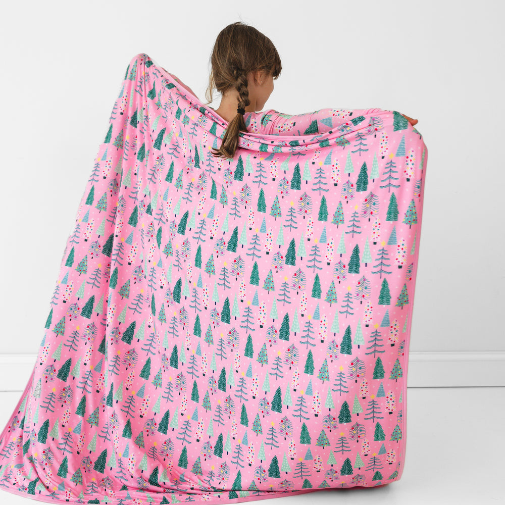 Back view image of a child holding out a Pink Twinkling Trees Large Cloud Blanket