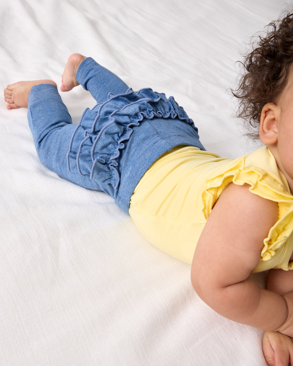 Baby on her tummy wearing the Heather Blue Ruffle Legging