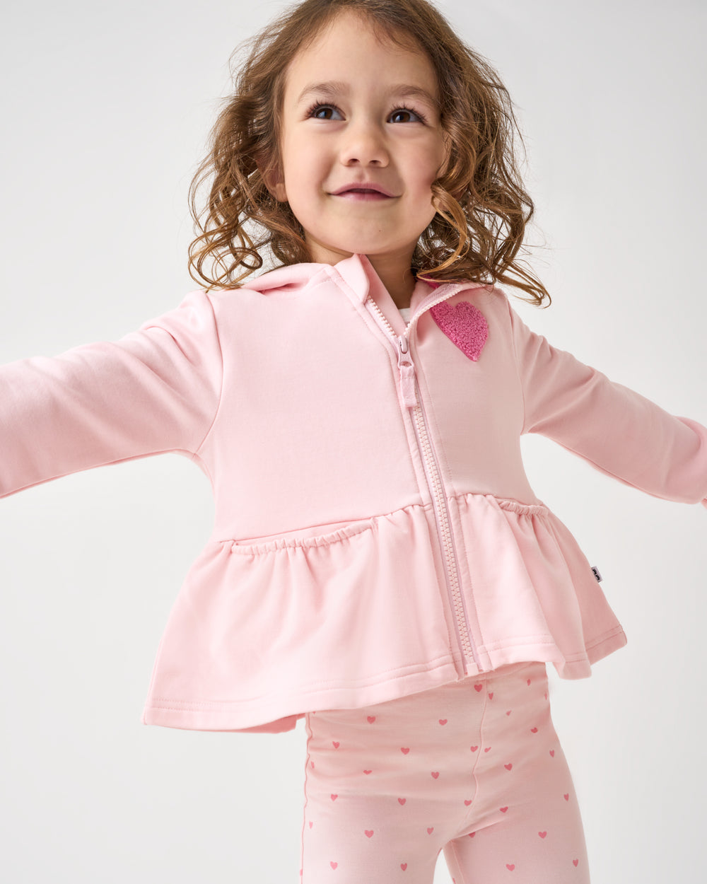 Posing child wearing the Little Love Flare Zip Hoodie