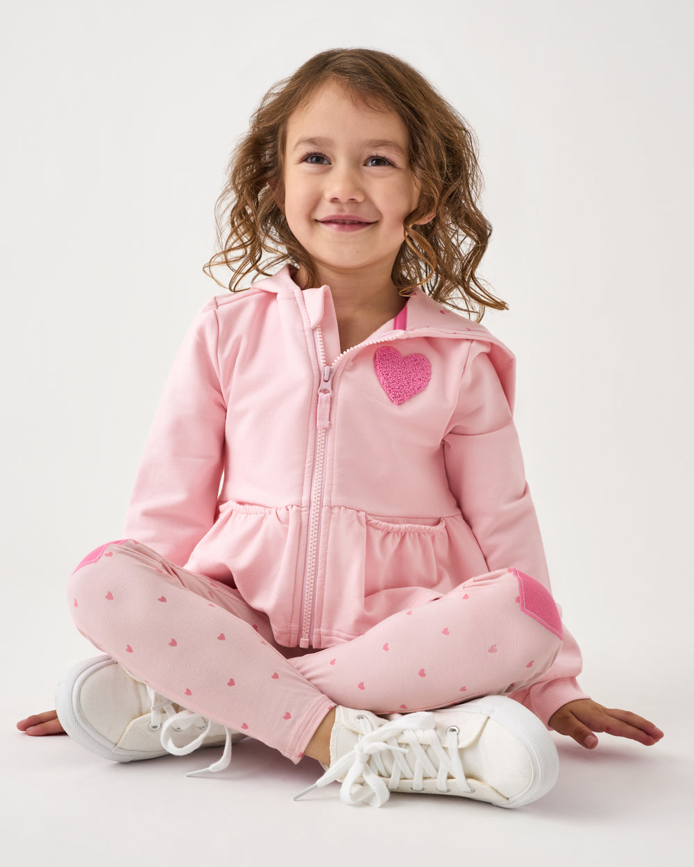 Sitting girl wearing the Little Love Flare Zip Hoodie