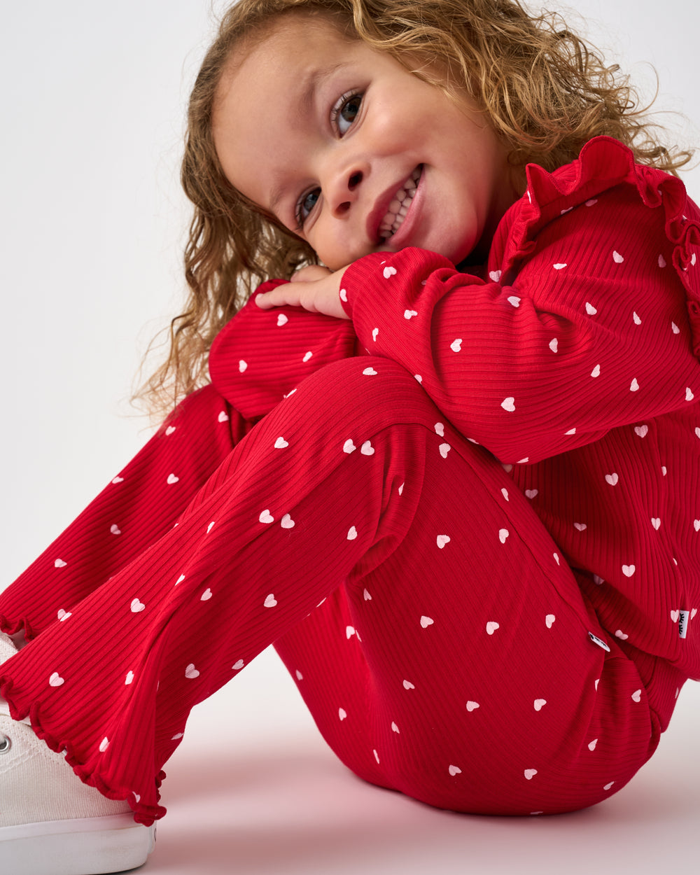 Sitting girl wearing the Little Love Ribbed Flare Pant and Flutter Sweatshirt