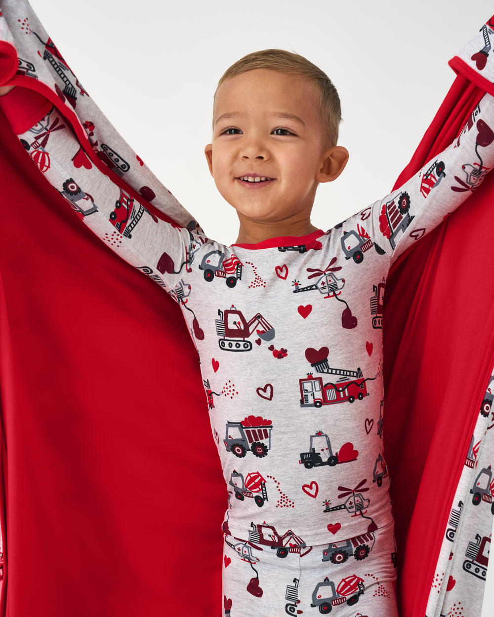 Boy holding up the Loads of Love Large Cloud Blanket® showing the solid red side