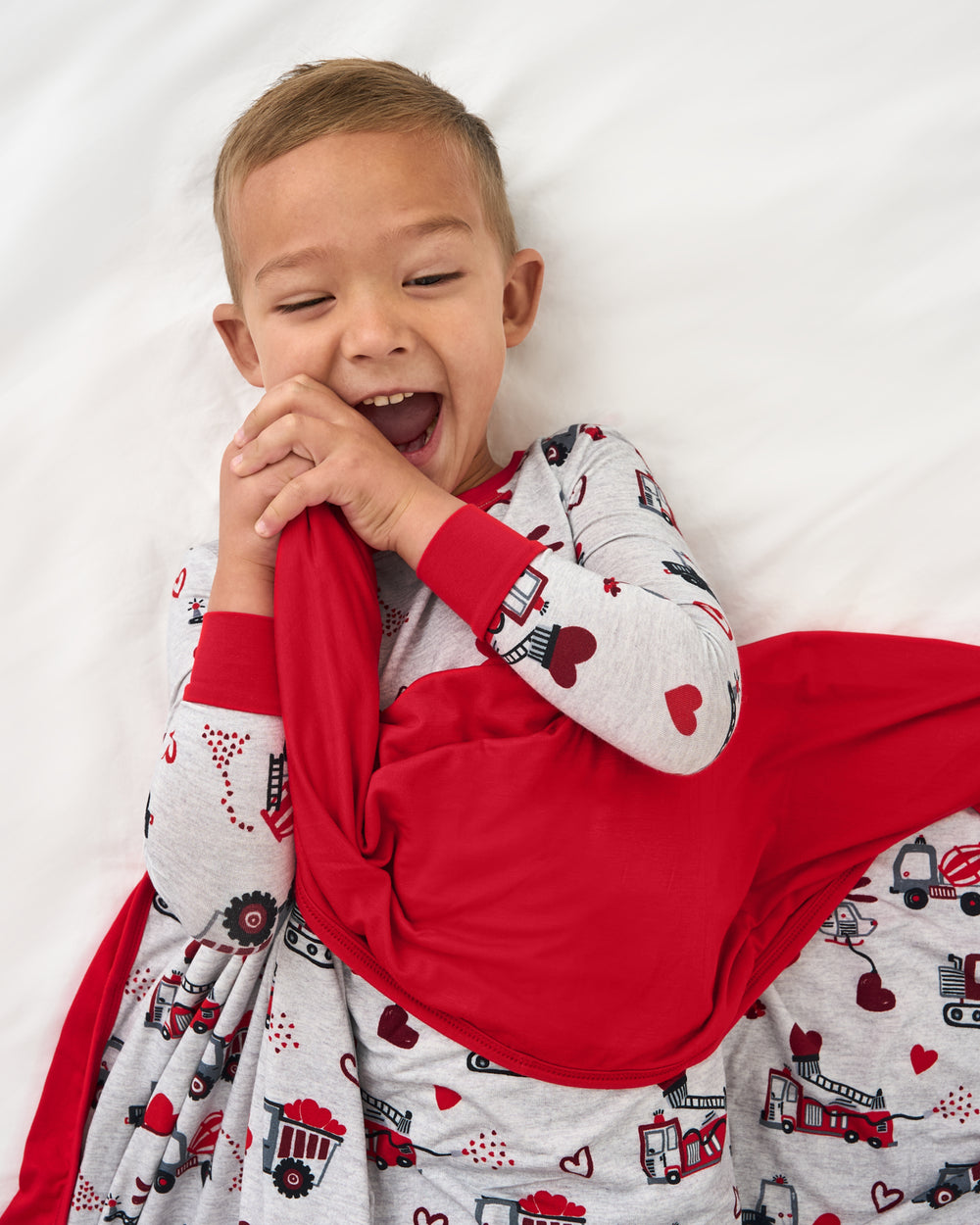 Child on a white bed wrapped in the Loads of Love Large Cloud Blanket®