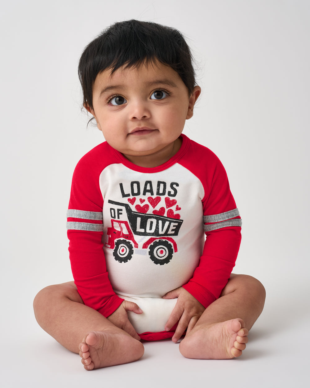 Sitting baby wearing the Loads of Love Raglan Bodysuit