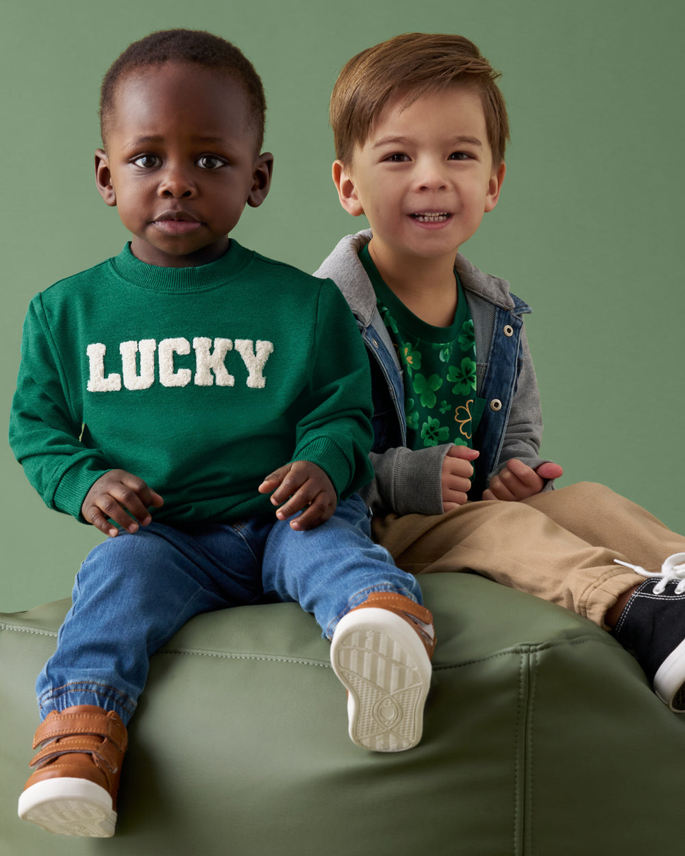 Two children on a green ottoman wearing styles from the St. Patricks day collecion
