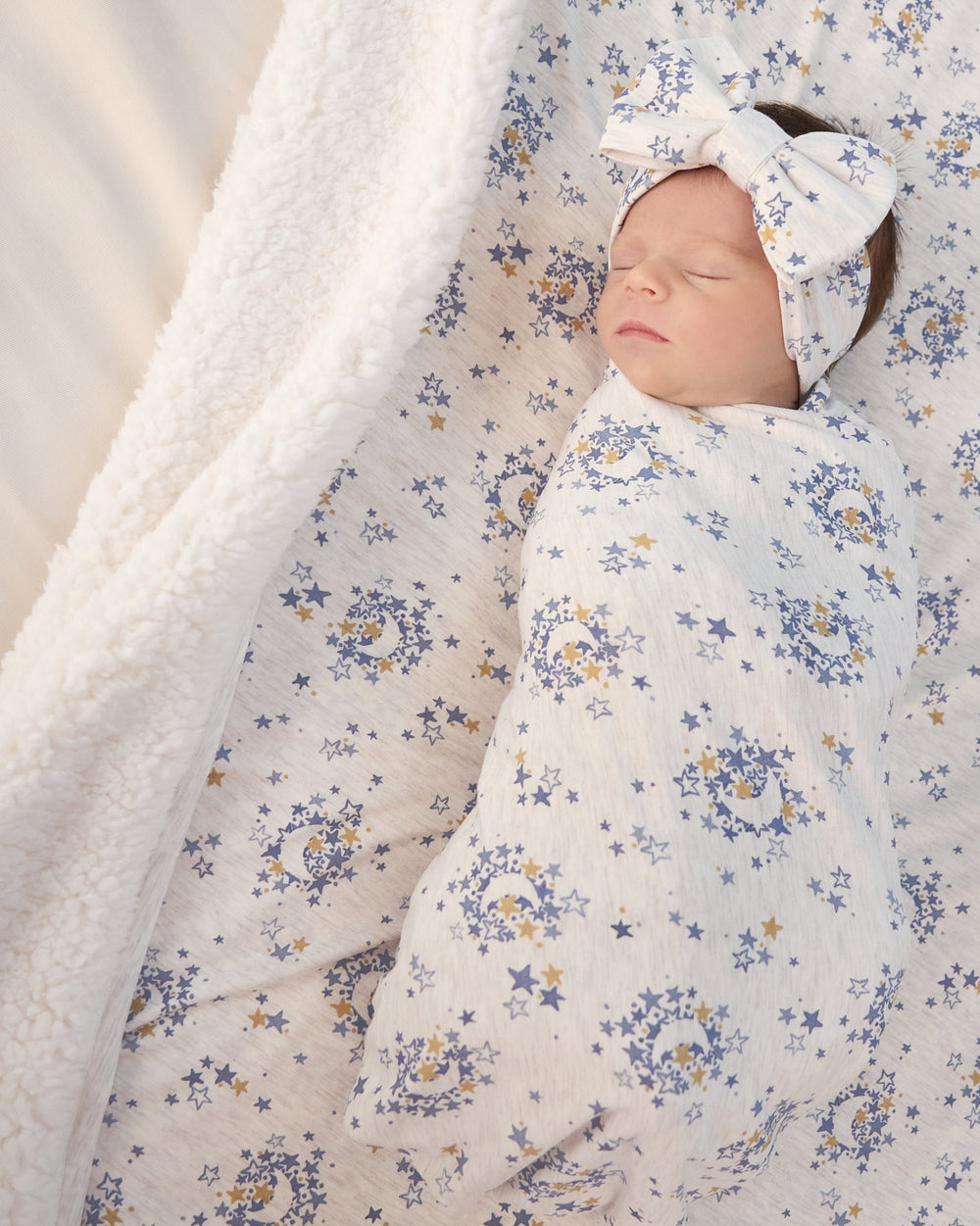 Aerial view of newborn in the Lullaby Sky Swaddle & Luxe Bow Headband Set on the matching Cloud Blanket