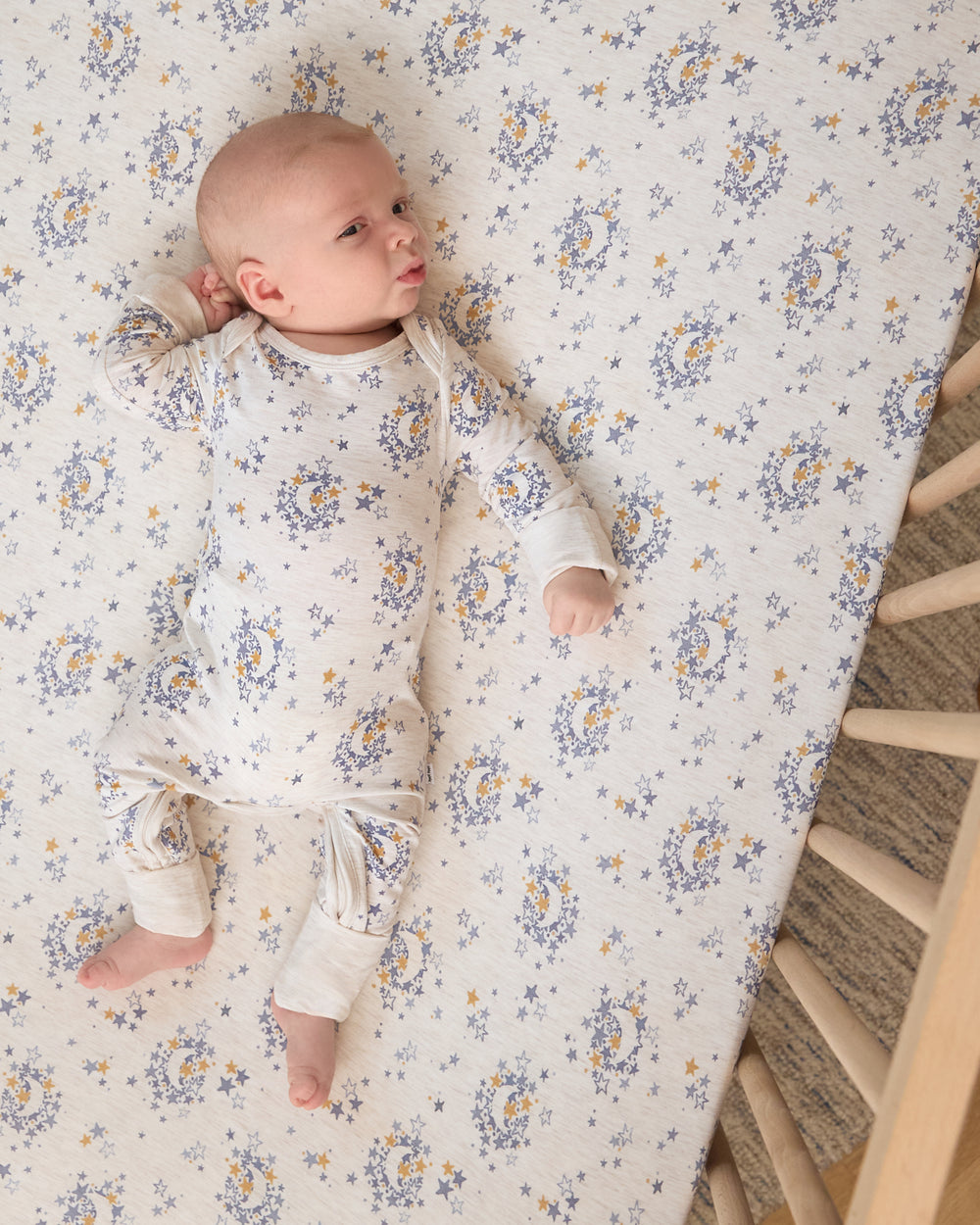 Overhead view of baby in a crib with the Lullaby Sky Fitted Crib Sheet