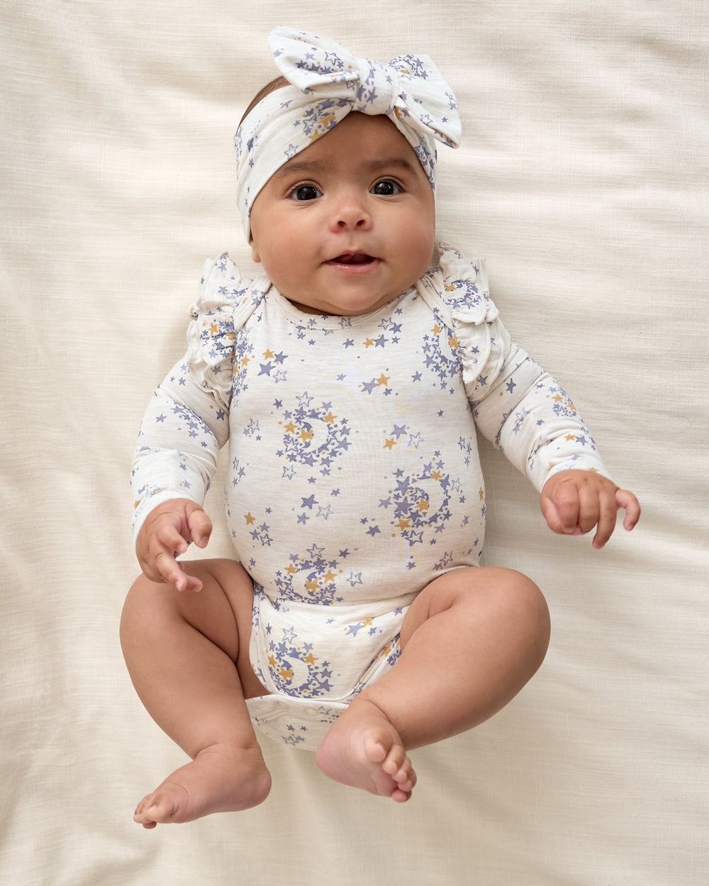Newborn wearing the Lullaby Sky Luxe Bow Headband and girls snap bodysuit
