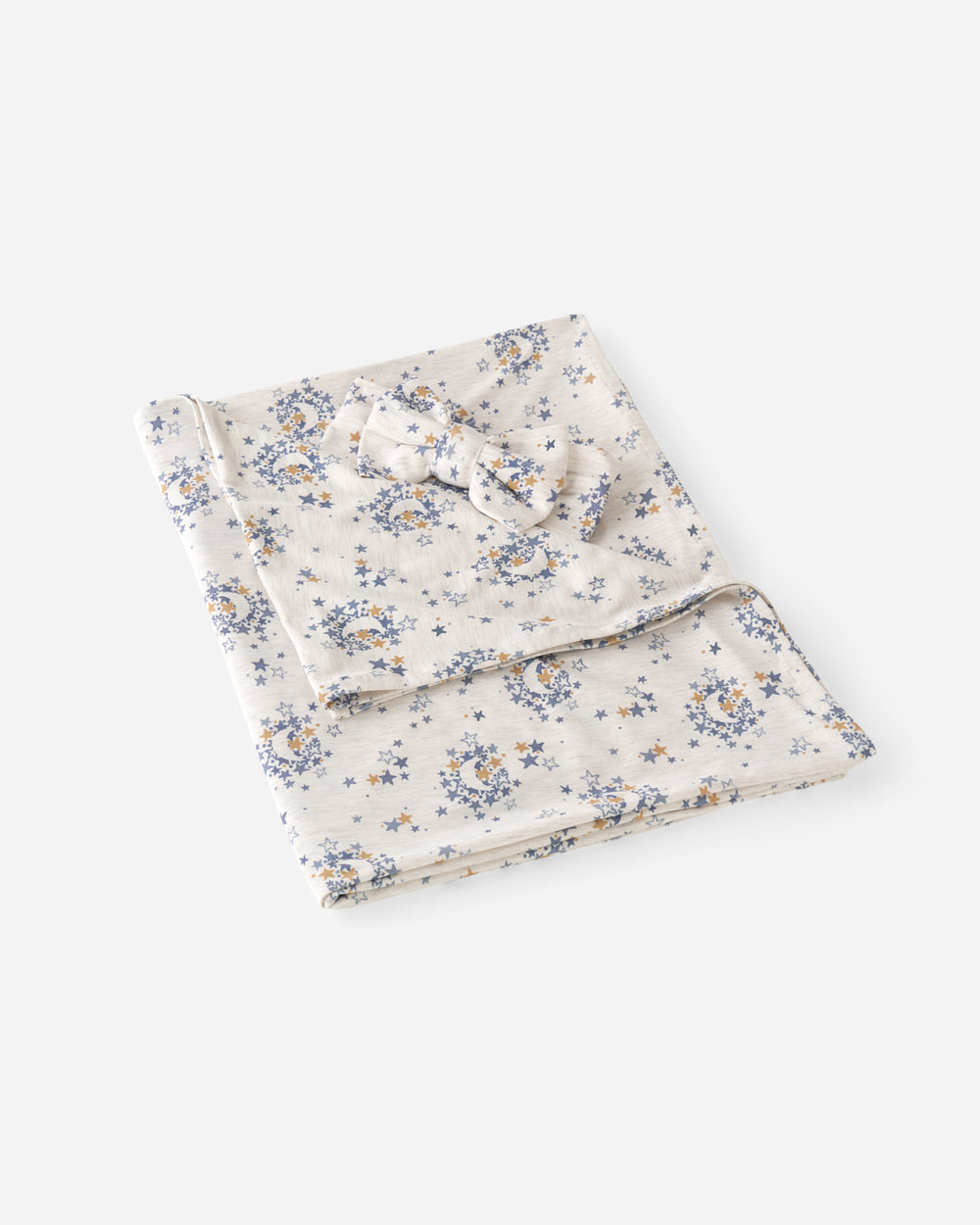 Flat lay of the Lullaby Sky Swaddle & Luxe Bow Headband Set