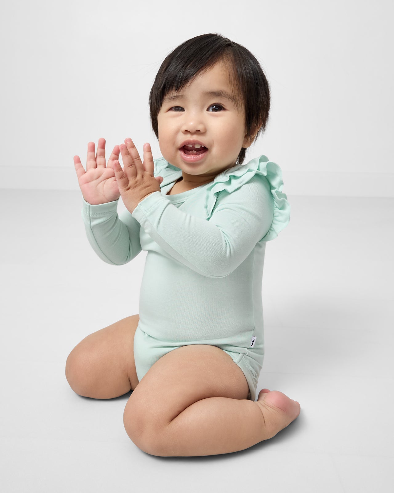 Clapping baby wearing the Mint Mist Flutter Bodysuit