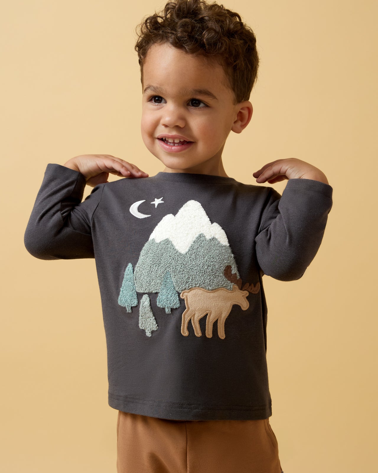 Boy wearing the Moose Trail Long Sleeve Relaxed Tee on a yellow background
