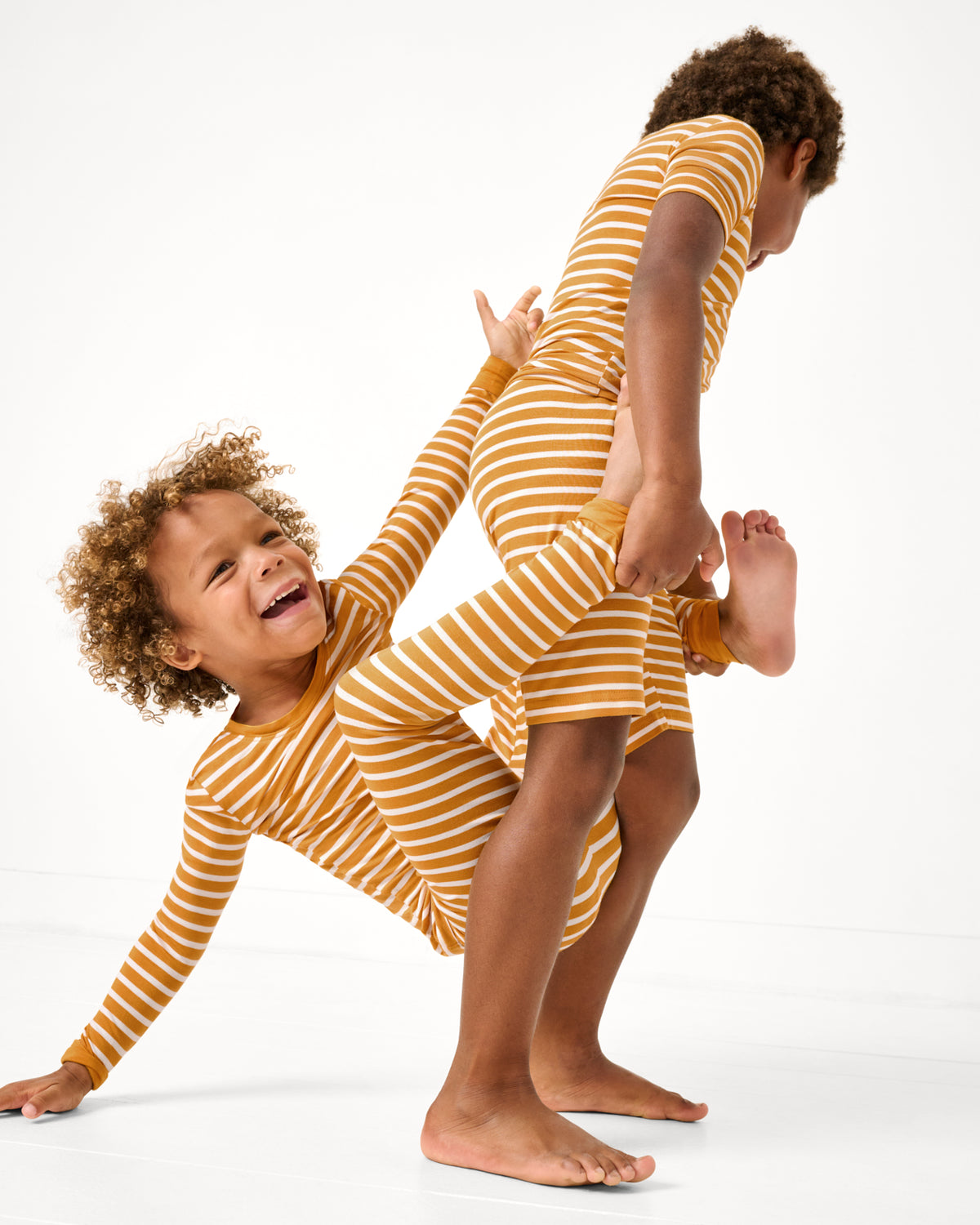 Two children wearing matching Marigold Stripe Two-Piece Pajama Sets