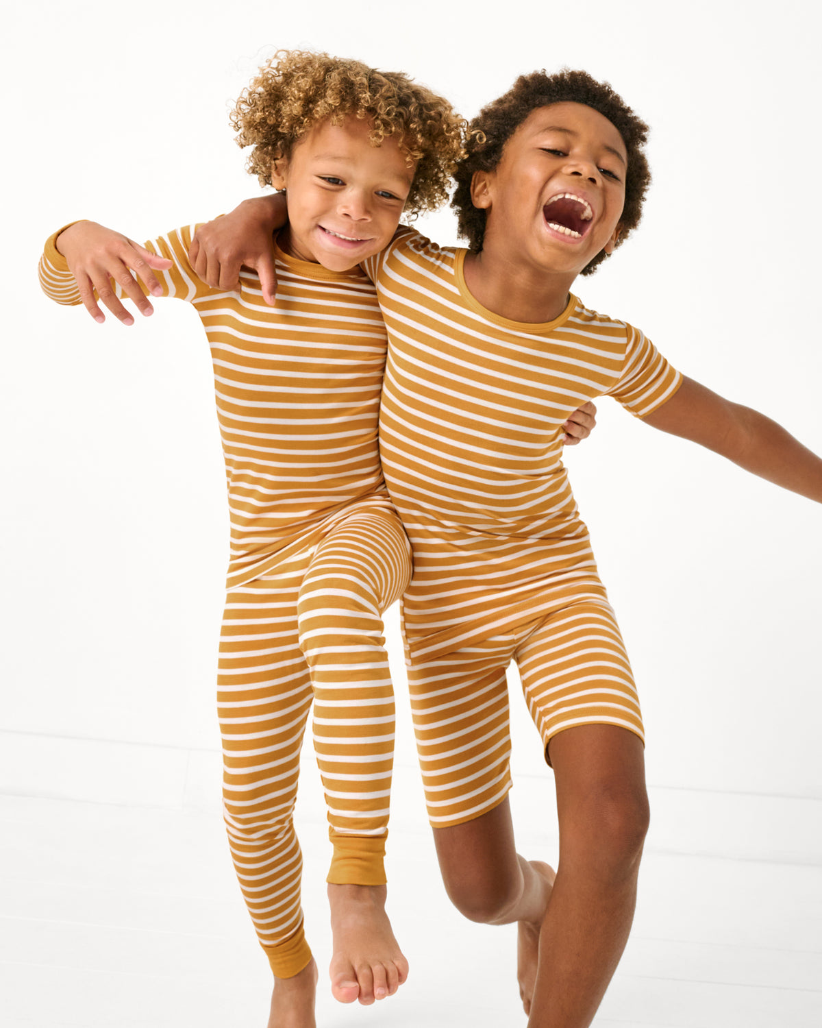 Two kids wearing matching Marigold Stripe Two-Piece Pajama Sets