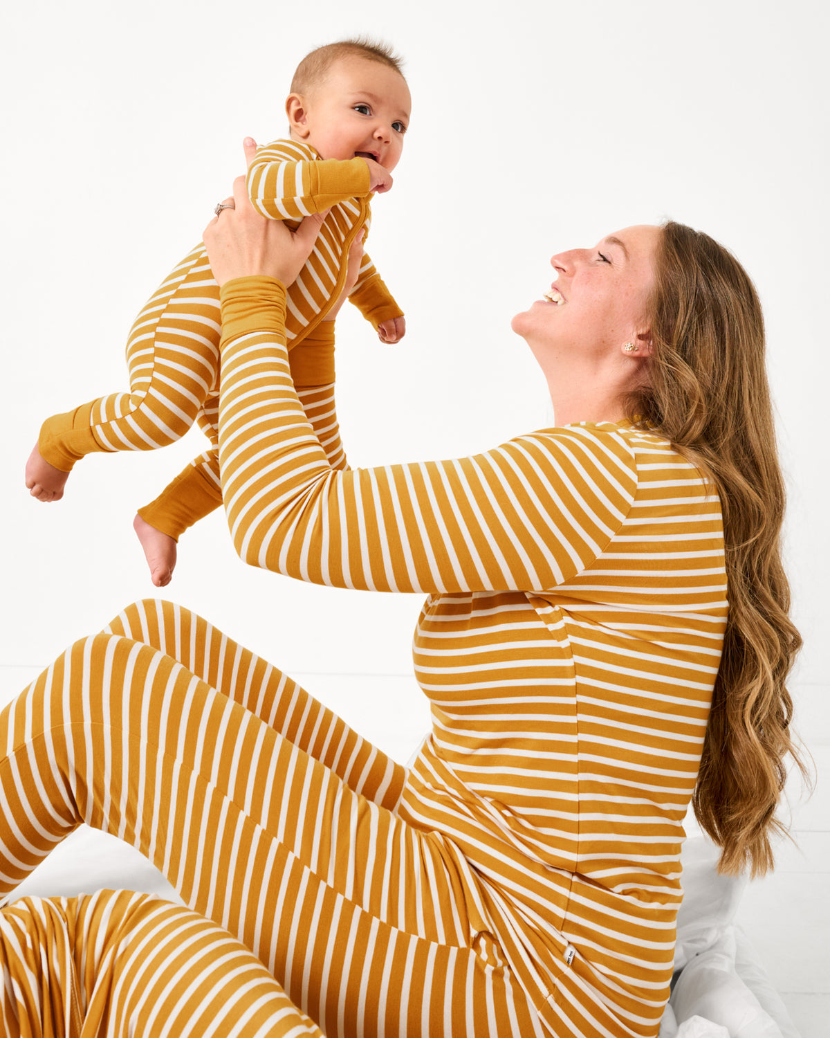 Mother holding up baby wearing matching Marigold Stripe pajamas