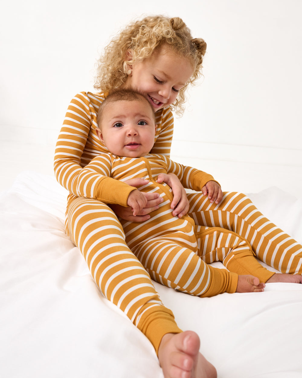 Two children wearing matching Marigold Stripe pajamas