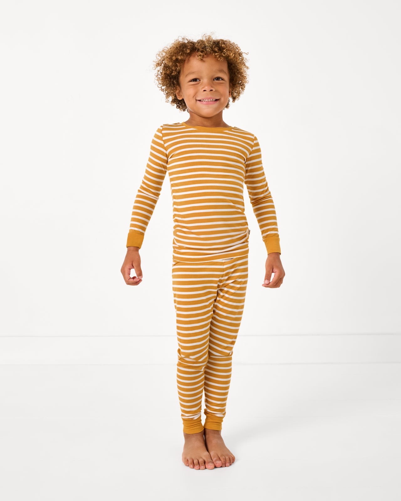 Standing boy wearing the Marigold Stripe Two-Piece Pajama Set