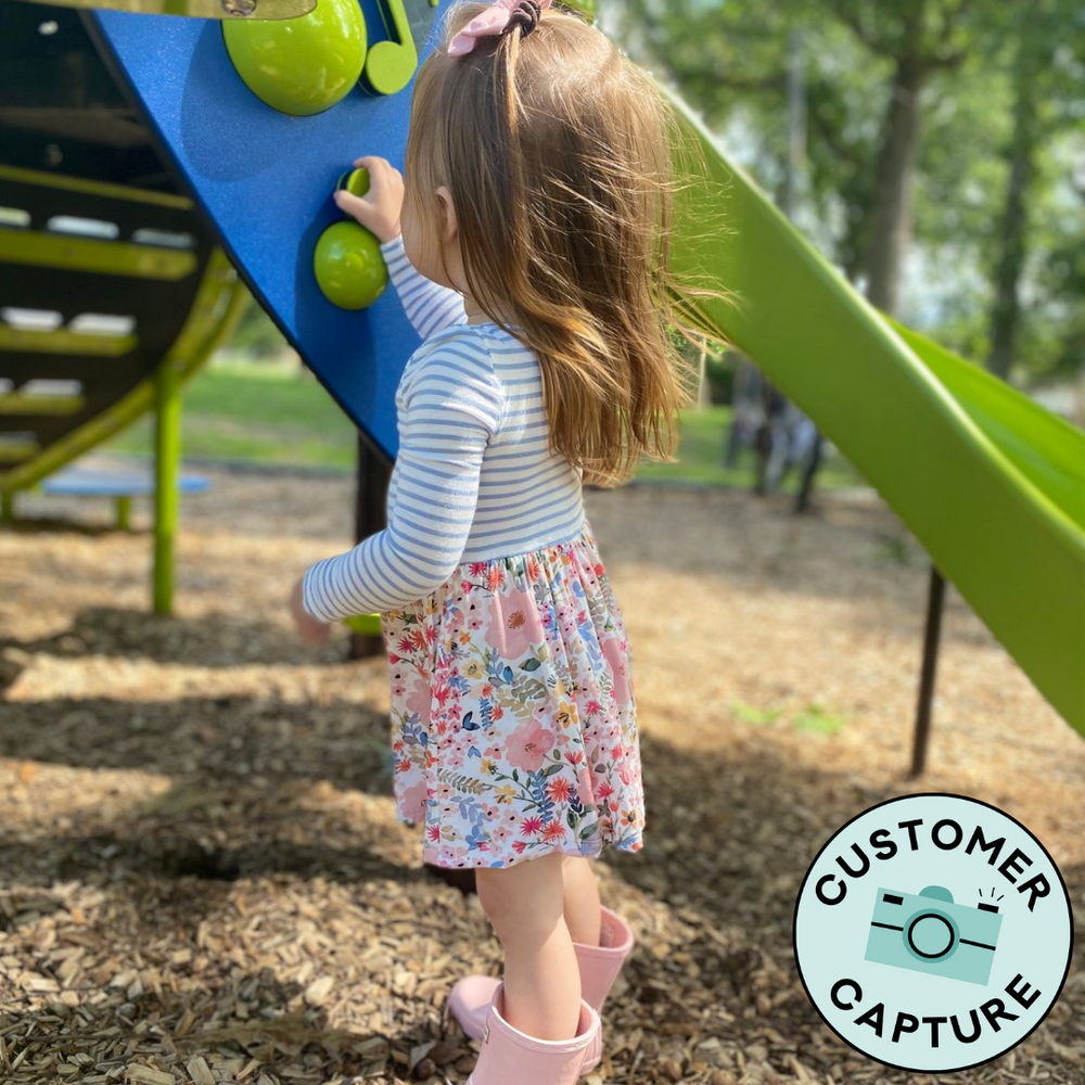 Customer Capture of a child at a playground wearing a Mauve Meadow Stripes Skater dress with bodysuit