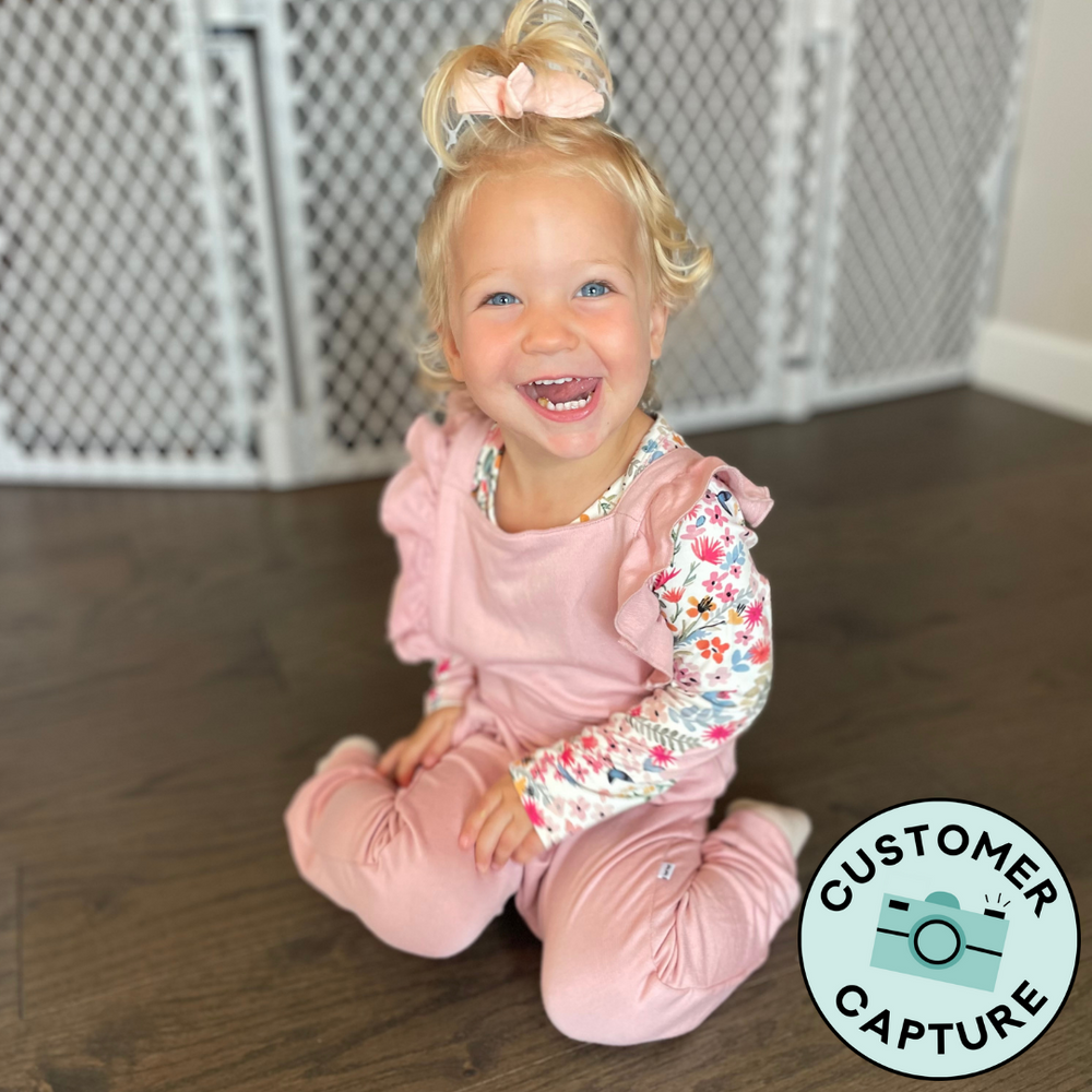 Click to see full screen - Customer Capture image of a child wearing Mauve Blush Ruffle Overalls paired with a Mauve Meadow bodysuit