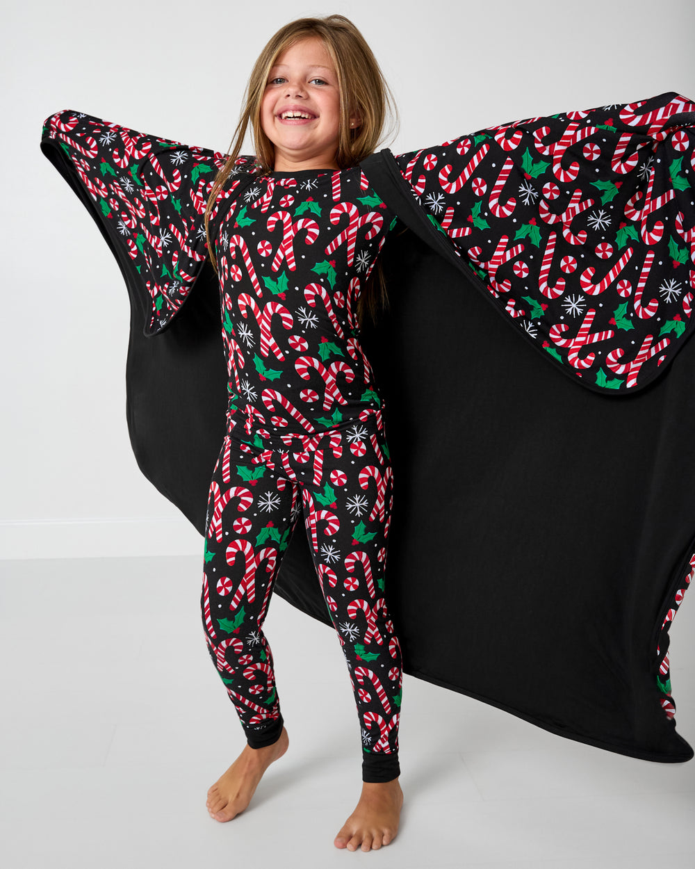 Girl holding up the Merry Mints Large Cloud Blanket® showing the solid black side