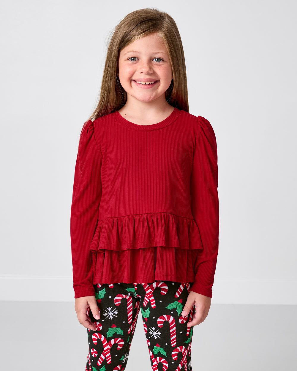 Girl wearing the Holiday Red Ribbed Tiered Peplum Top with merry mint print leggings