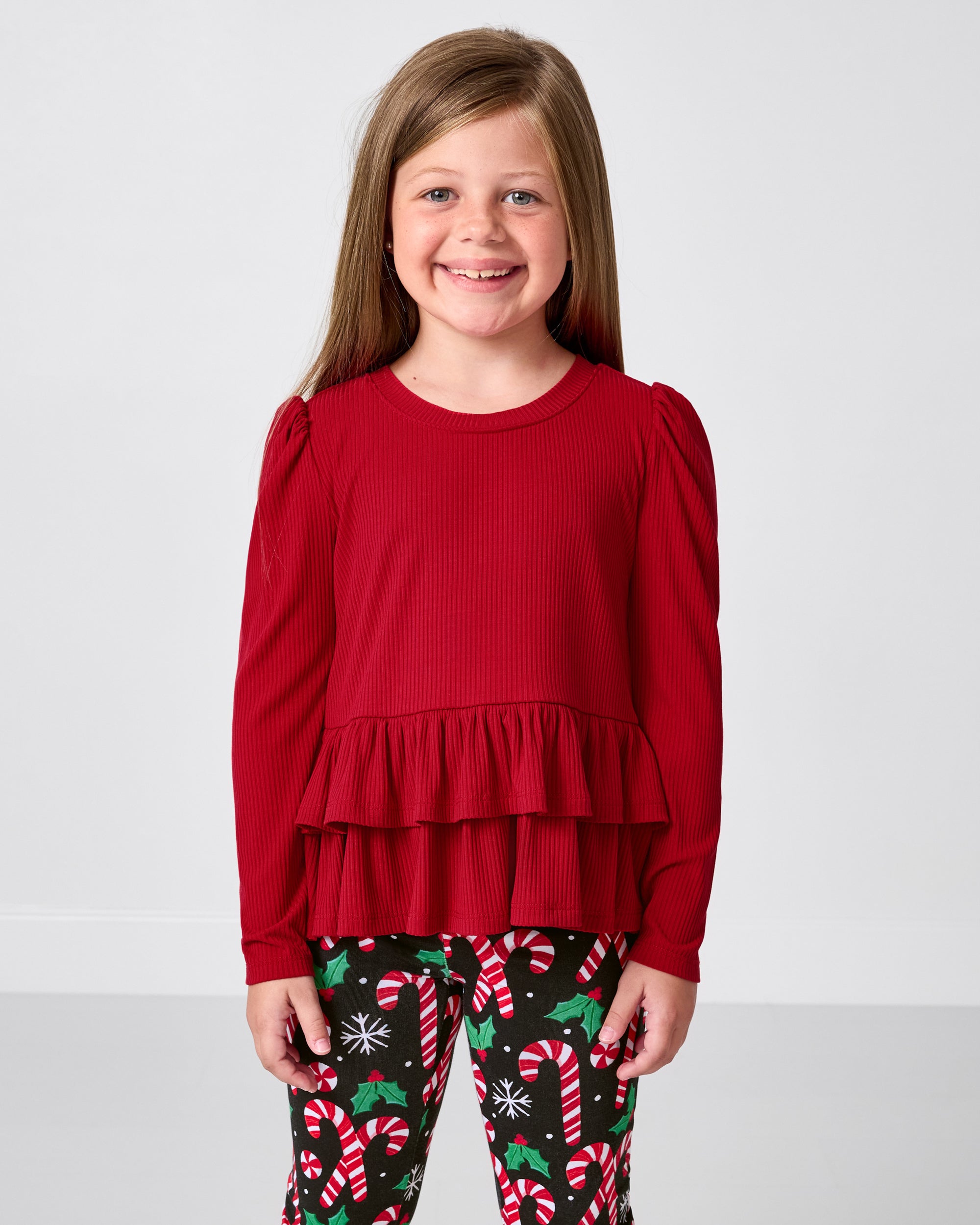 Girl wearing the Holiday Red Ribbed Tiered Peplum Top with merry mint print leggings