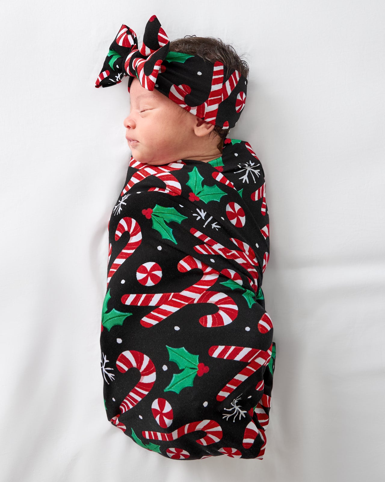 Baby swaddled in the Merry Mints Swaddle & Luxe Bow Headband Set
