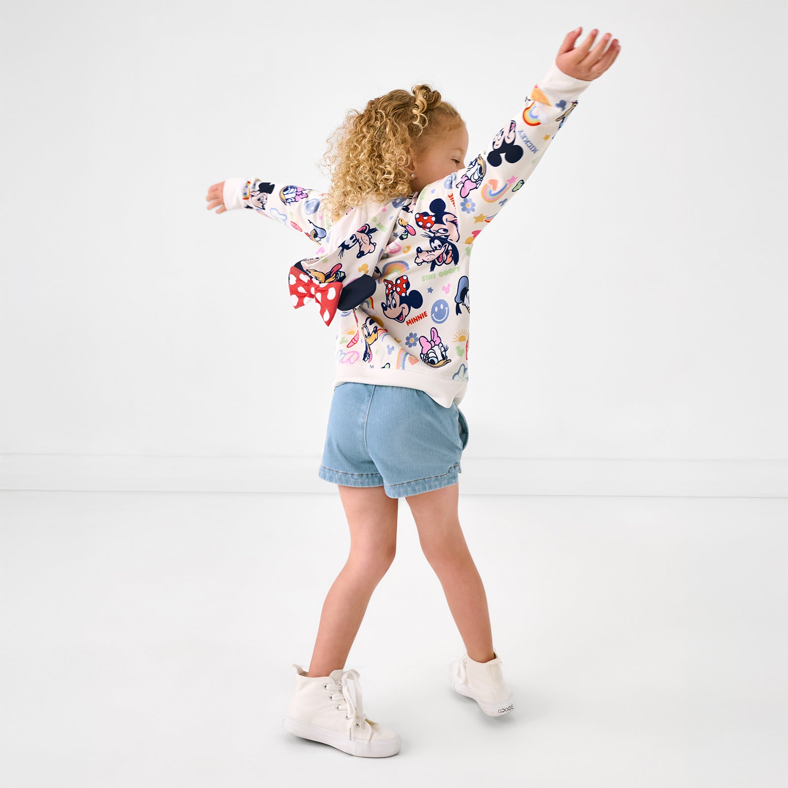 Posing girl wearing the Disney Mickey's Clubhouse Minnie Zip Hoodie with denim girls shorts