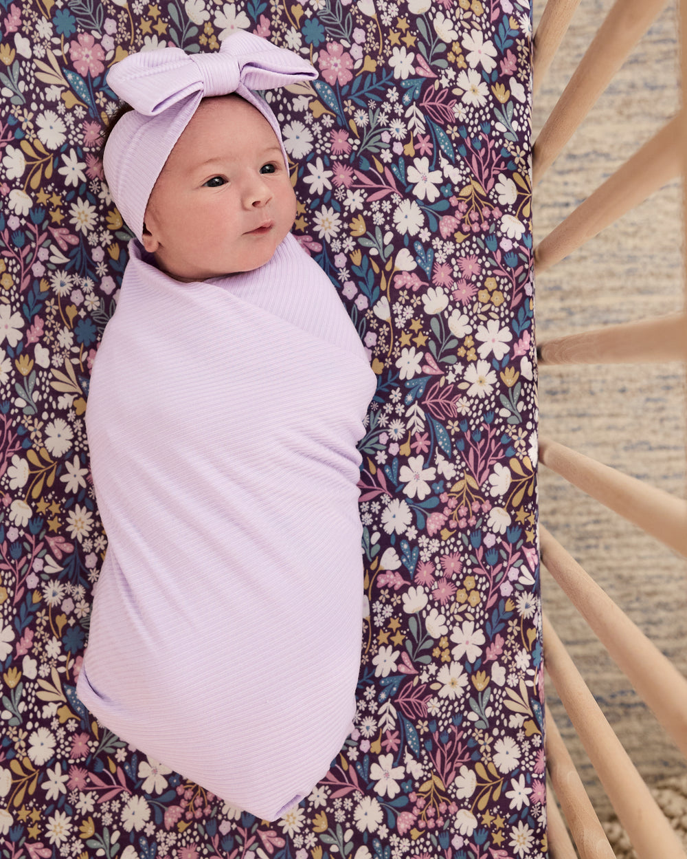 Newborn laying on the Midnight Petals Fitted Crib Sheet