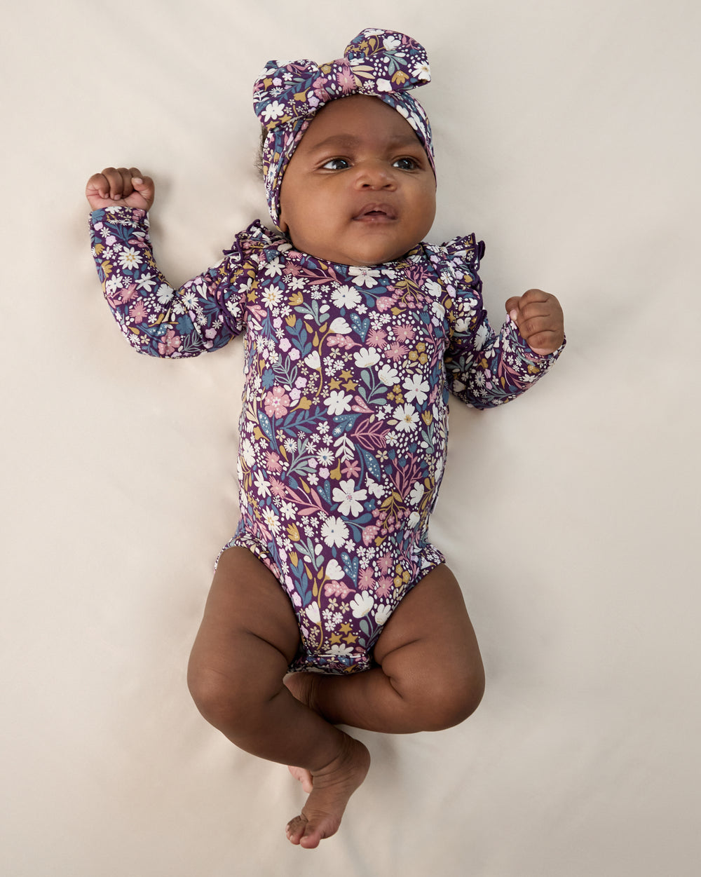Aerial view of baby wearing the Midnight Petals Luxe Bow Headband and Bodysuit