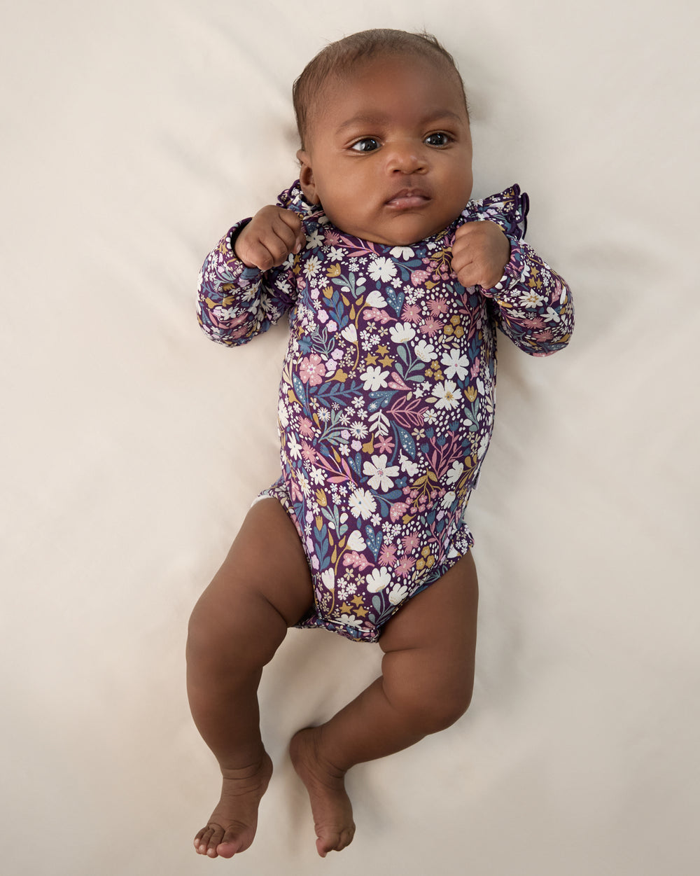 Aerial view of newborn wearing the Midnight Petals Flutter Bodysuit