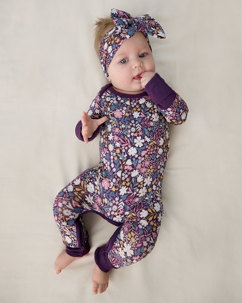 Aerial view of baby wearing the Midnight Petals Crescent Zippy and Luxe Bow