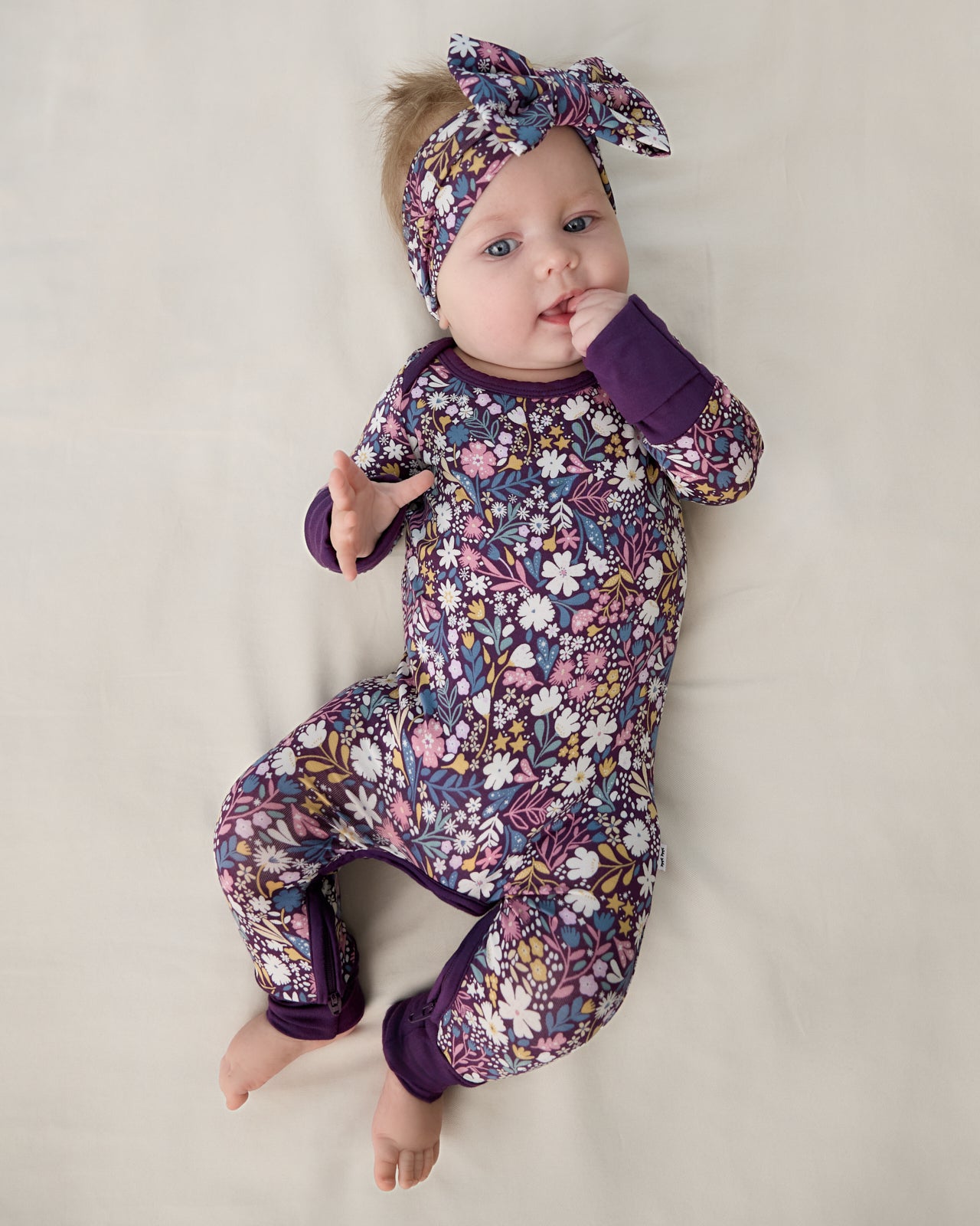 Aerial view of baby wearing the Midnight Petals Crescent Zippy and Luxe Bow