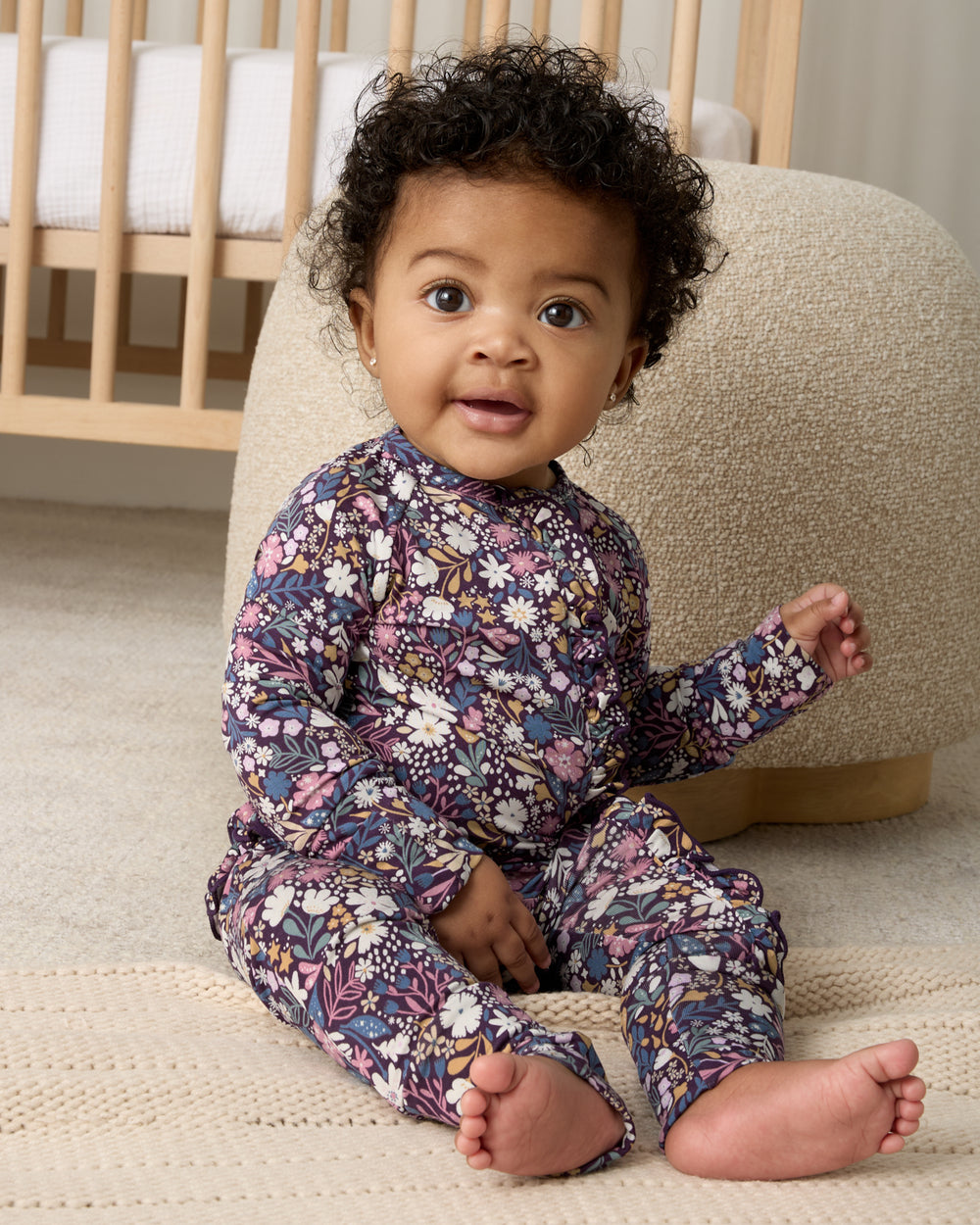 Sitting baby wearing the Midnight Petals Ruffle Zippy