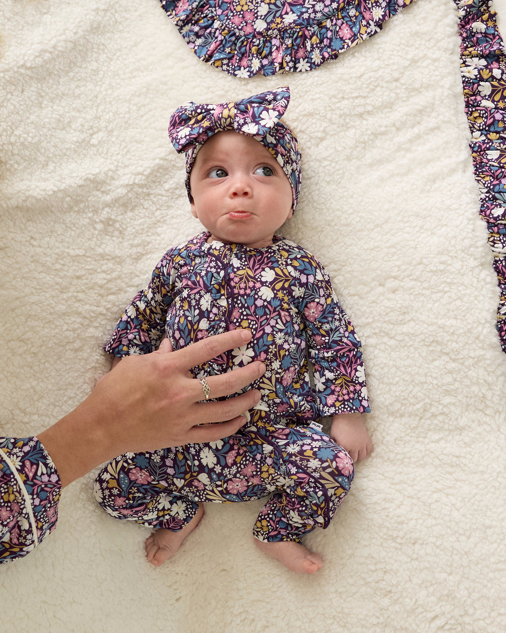 Aerial view of newborn wearing the Midnight Petals Ruffle Zippy on a sherpa blanket