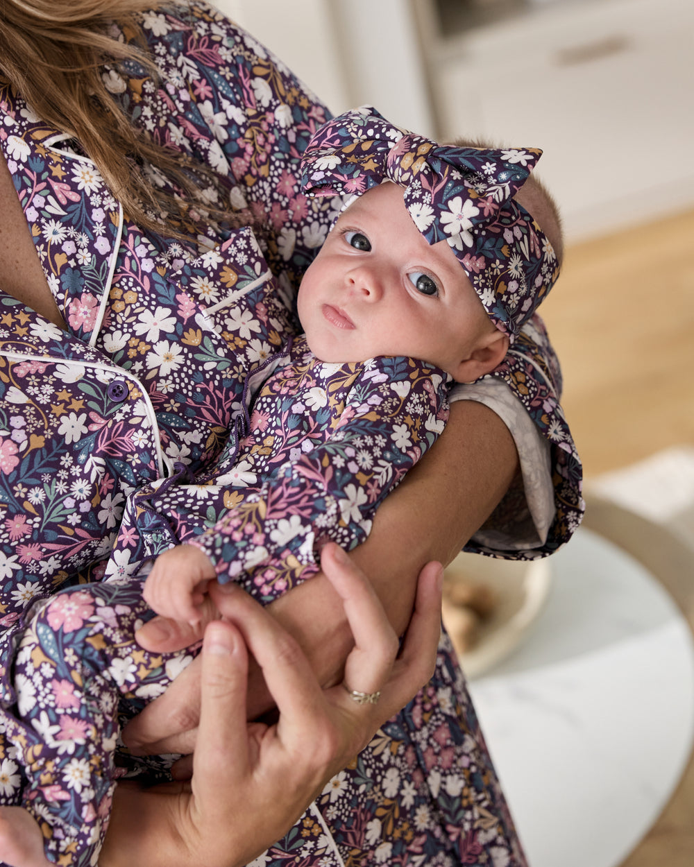Mother holding newborn wearing the Midnight Petals Luxe Bow Headband