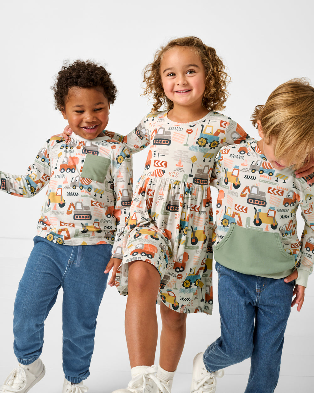 Three children wearing matching Mini Builders construction themed clothing