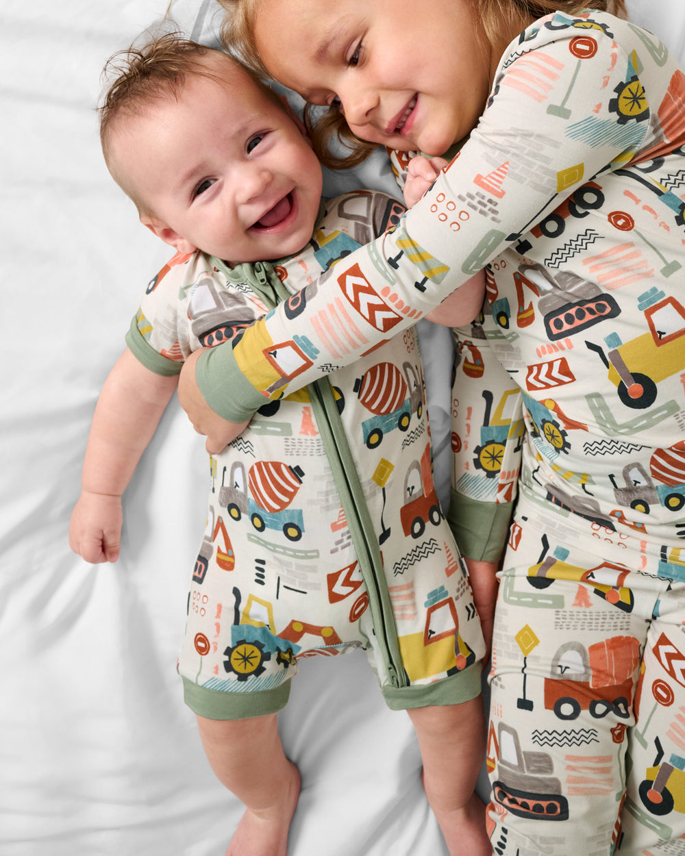 Two children wearing matching Mini Builders construction themed pajamas