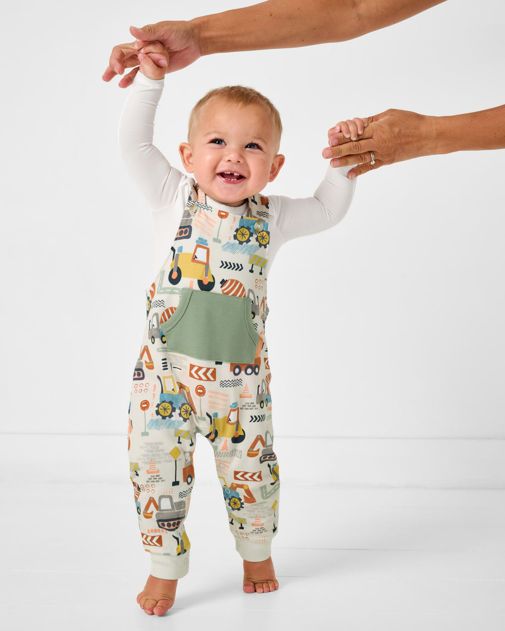 Walking baby wearing the Mini Builders Overall Romper