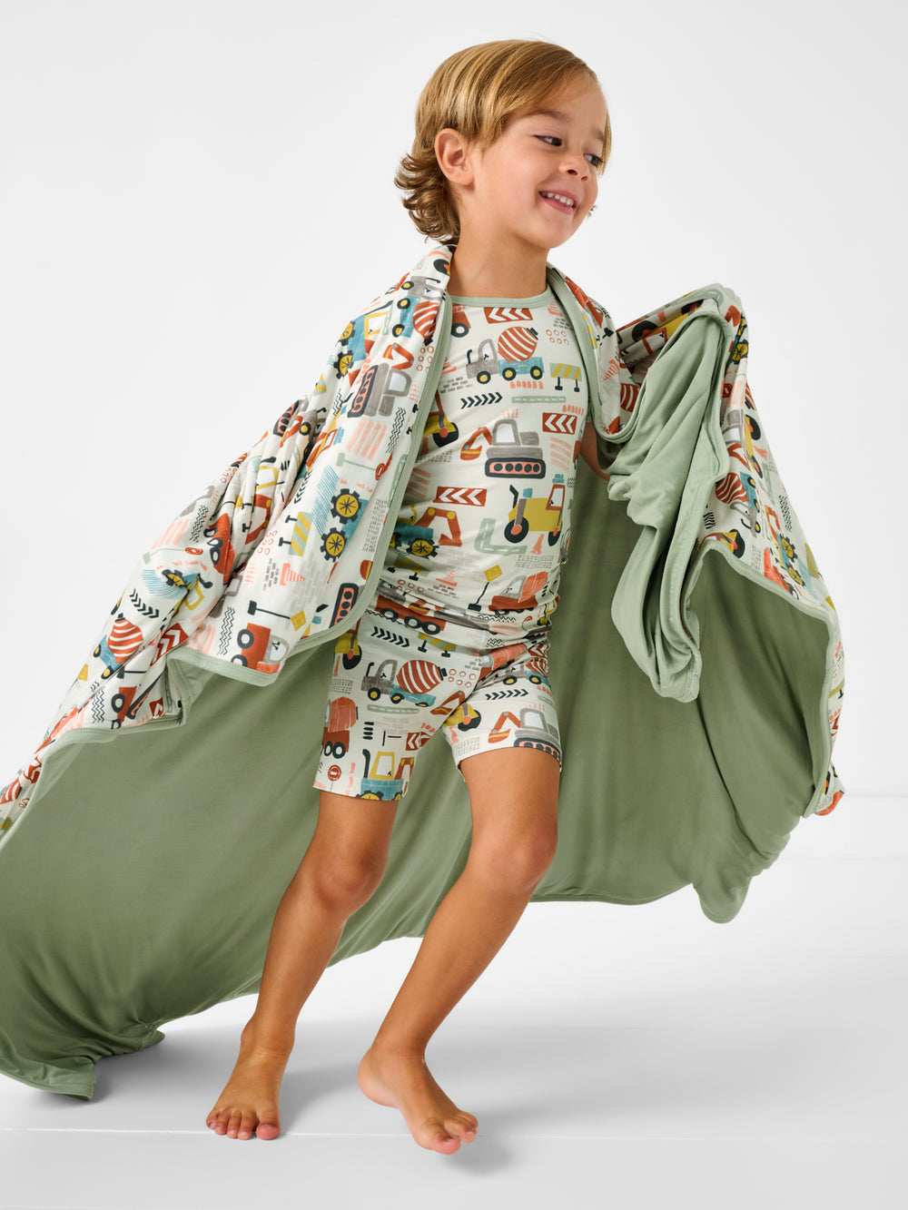 Child in motion wrapped in the Mini Builders Large Cloud Blanket®
