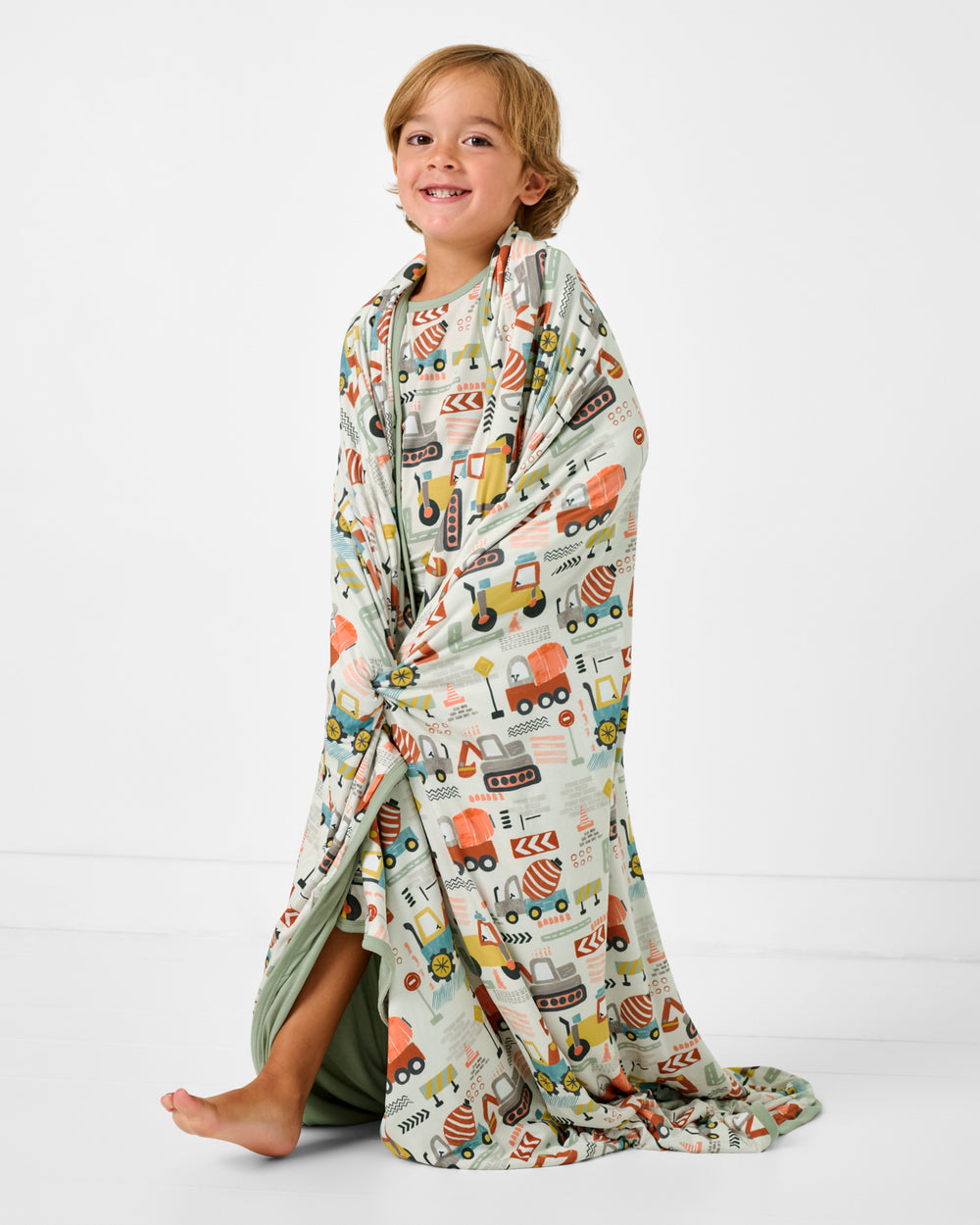 Standing boy wrapped in the Mini Builders Large Cloud Blanket®