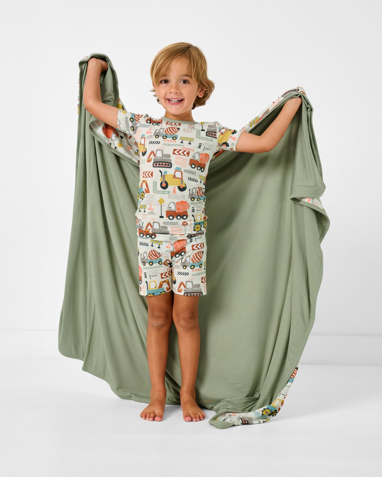 Boy holding up the Mini Builders Large Cloud Blanket® showing the solid green side