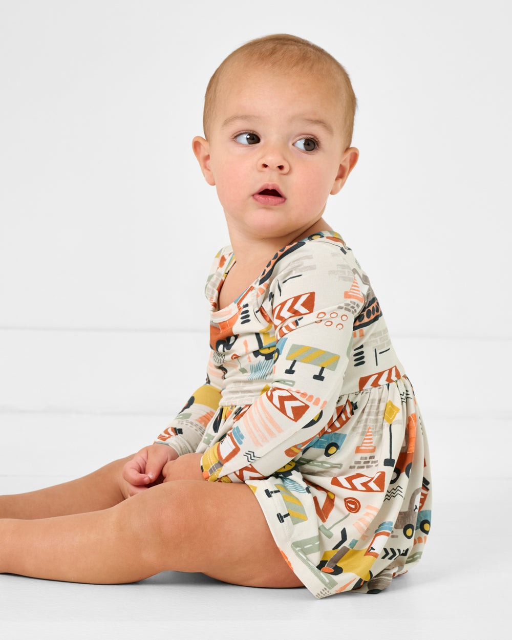 Sitting baby wearing the Mini Builders Skater Dress with Bodysuit