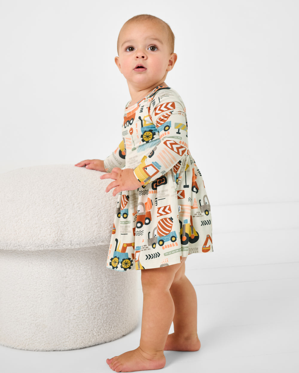 Standing baby wearing the Mini Builders Skater Dress with Bodysuit