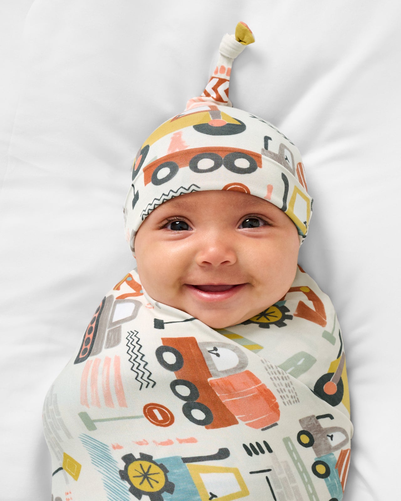 Close up of baby wearing the Mini Builders Swaddle & Hat Set