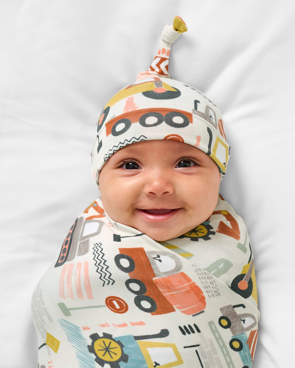 Close up of baby wearing the Mini Builders Swaddle & Hat Set